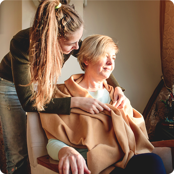 Young woman wrapping blanket around senior