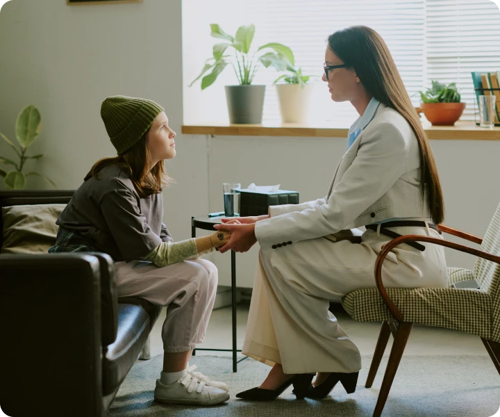 Woman holding hands with child in counseling
